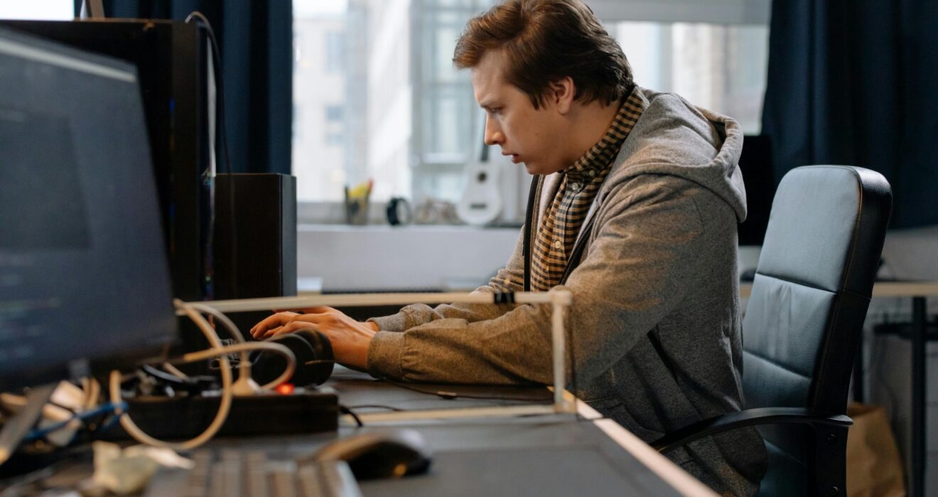 Free A concentrated professional working at a computer in a modern office setting. Stock Photo